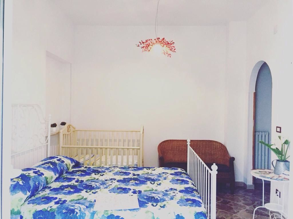 Una camera da letto con un letto, una culla, una sedia e un tavolino con una pianta.