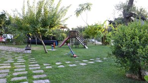 A playground with a slide and climbing structures, surrounded by grass and trees. - B&B SanteBice (Polignano a Mare)