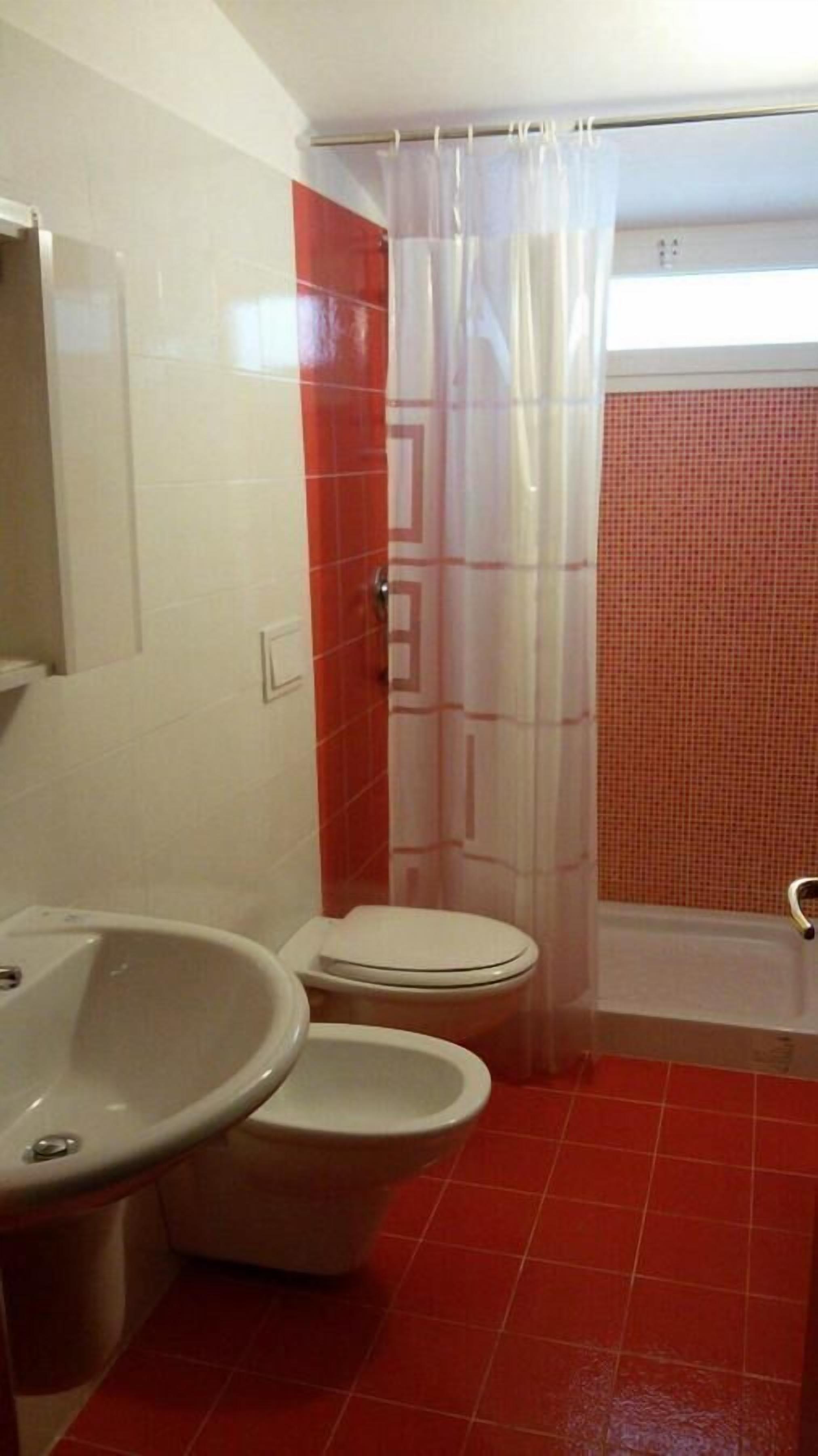 Un bagno con WC, lavandino e tenda doccia.