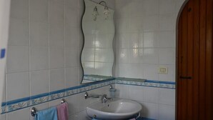 A bathroom with a white sink, a mirror, and a wooden door. - B&B SanteBice (Polignano a Mare)