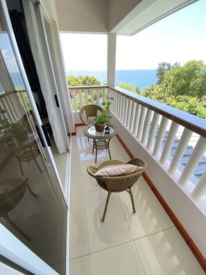 A balcony with wicker chairs, a small table, and a potted plant. - Dusk to Dawn (Mahé Island)