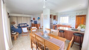 Een ruime woonkamer met een eettafel, stoelen, een bank en een keuken met een bar.