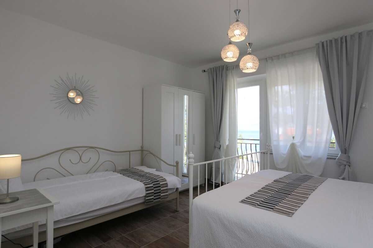 Une chambre avec deux lits, une table de chevet, une lampe, un élément décoratif mural et une fenêtre avec des rideaux.