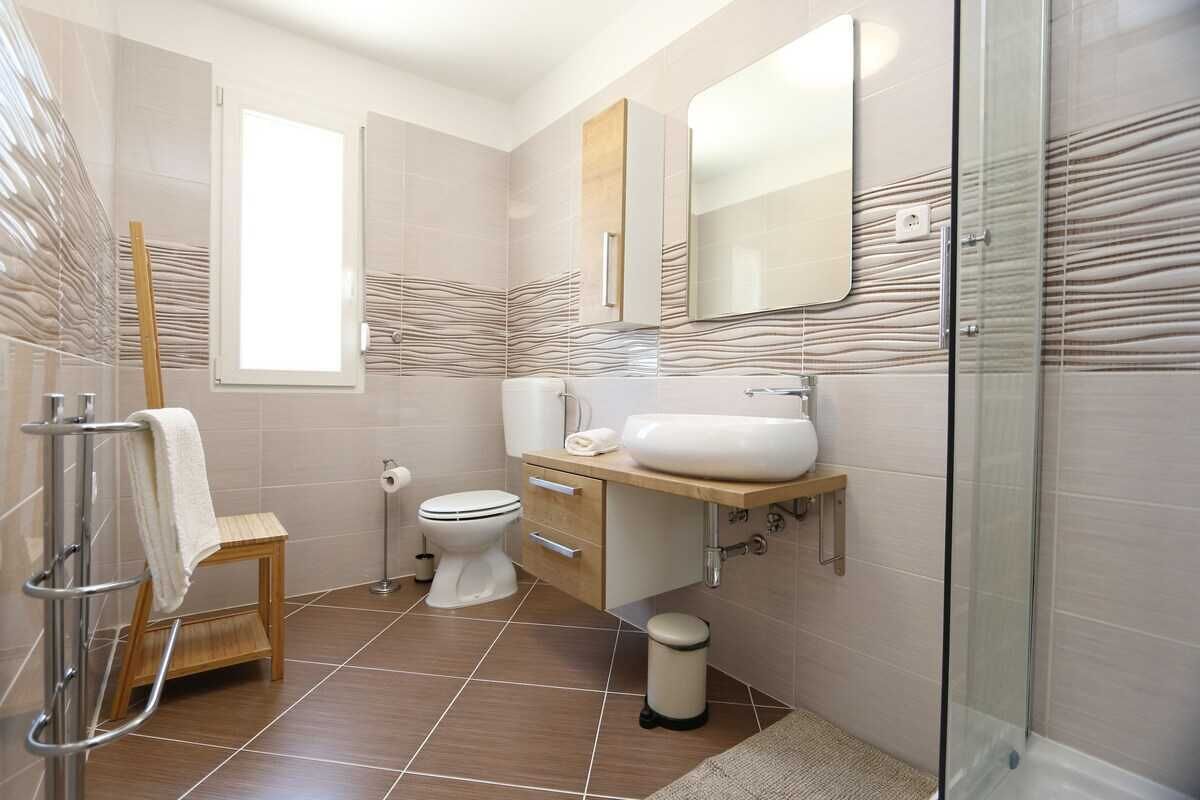 A modern bathroom with a toilet, sink, and shower.