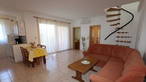 Un salon avec un canapé, une table à manger avec des chaises, un coin cuisine et un escalier en colimaçon.
