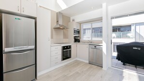 A modern kitchen with a stainless steel refrigerator, oven, microwave, and dishwasher. - Seaside Marine - Mt Maunganui Holiday Home (Mt Maunganui)