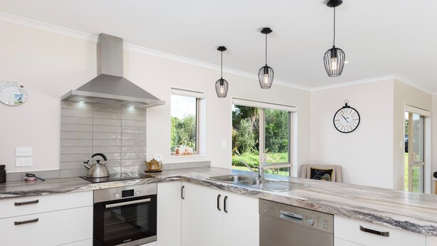 A modern kitchen with white cabinetry, a stainless steel oven, a Bosch dishwasher, and pendant lights.