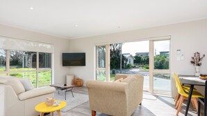 A modern living room with a sofa, a yellow side table, and a dining area with chairs.