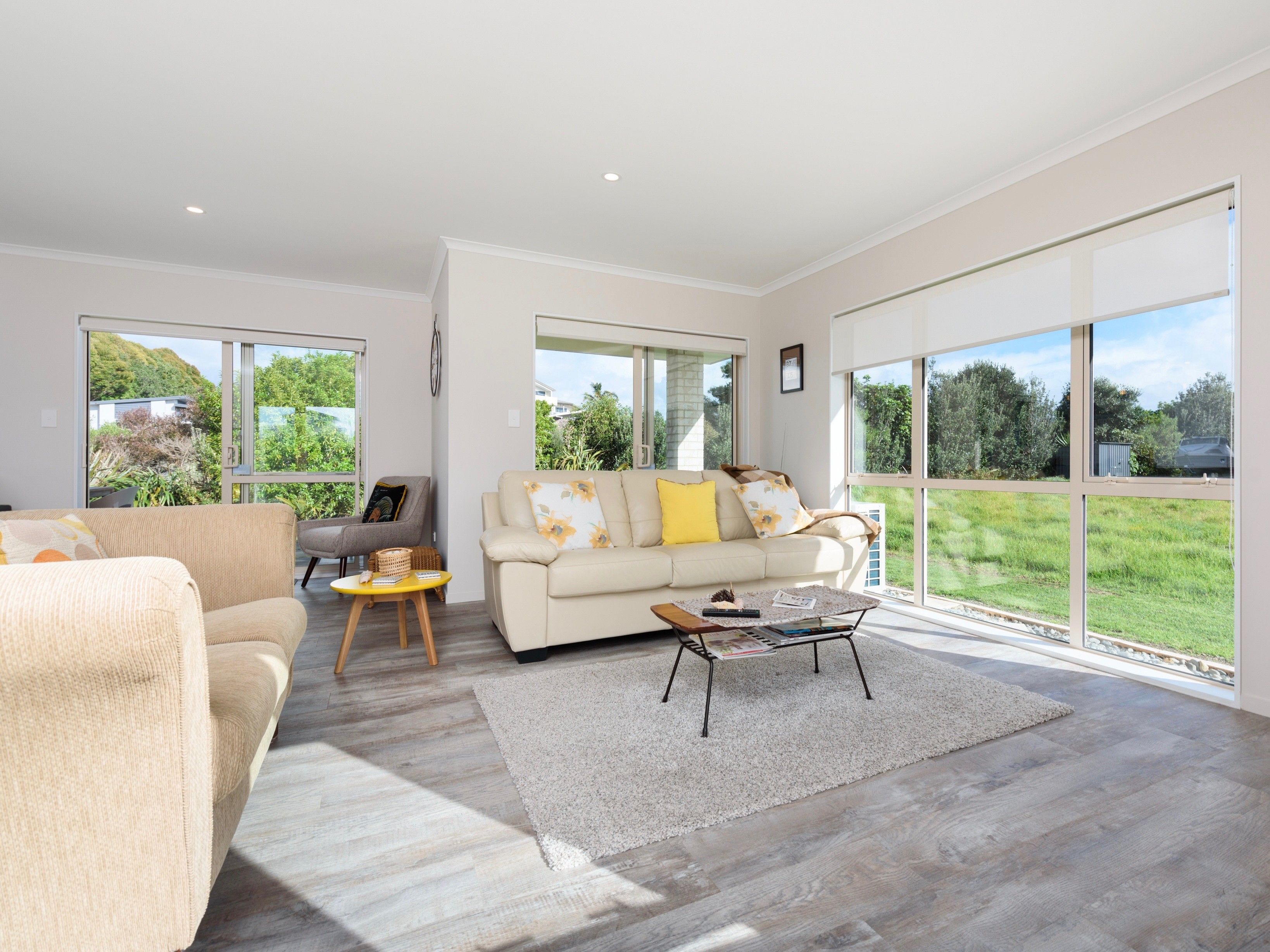 A spacious living room with a large window, a sofa, a coffee table, and a rug.
