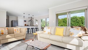 A modern living room with a sofa, coffee table, and a kitchen in the background.