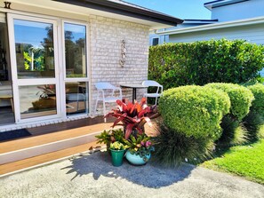 A patio area with a table and chairs, potted plants, and a well-maintained hedge.