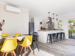A modern kitchen with a central island, black bar stools, and a dining area with yellow chairs.