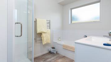 A modern bathroom with a glass shower enclosure, a bathtub, and a sink.
