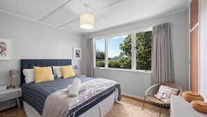 Une chambre à coucher avec un lit, une chaise, un bureau et une fenêtre avec des rideaux.