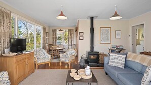 Un salon chaleureux avec une cheminée, des meubles en bois et de grandes fenêtres.
