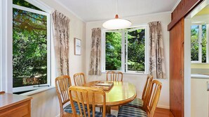Un coin repas comprenant une table ronde en bois, six chaises et un lustre.