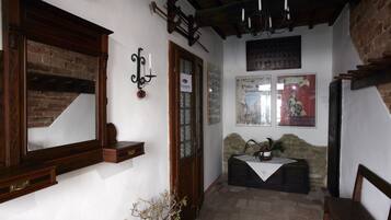 A cozy interior with a brick fireplace, wooden shelves, and a stone bench.