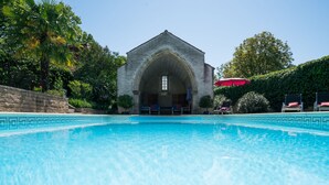 Una piscina con un edificio de piedra al fondo.