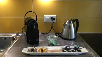 Uma bancada de cozinha com cafeteira, chaleira e um prato de doces.