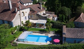 A residential area with a swimming pool, a covered patio, and a view of surrounding houses.