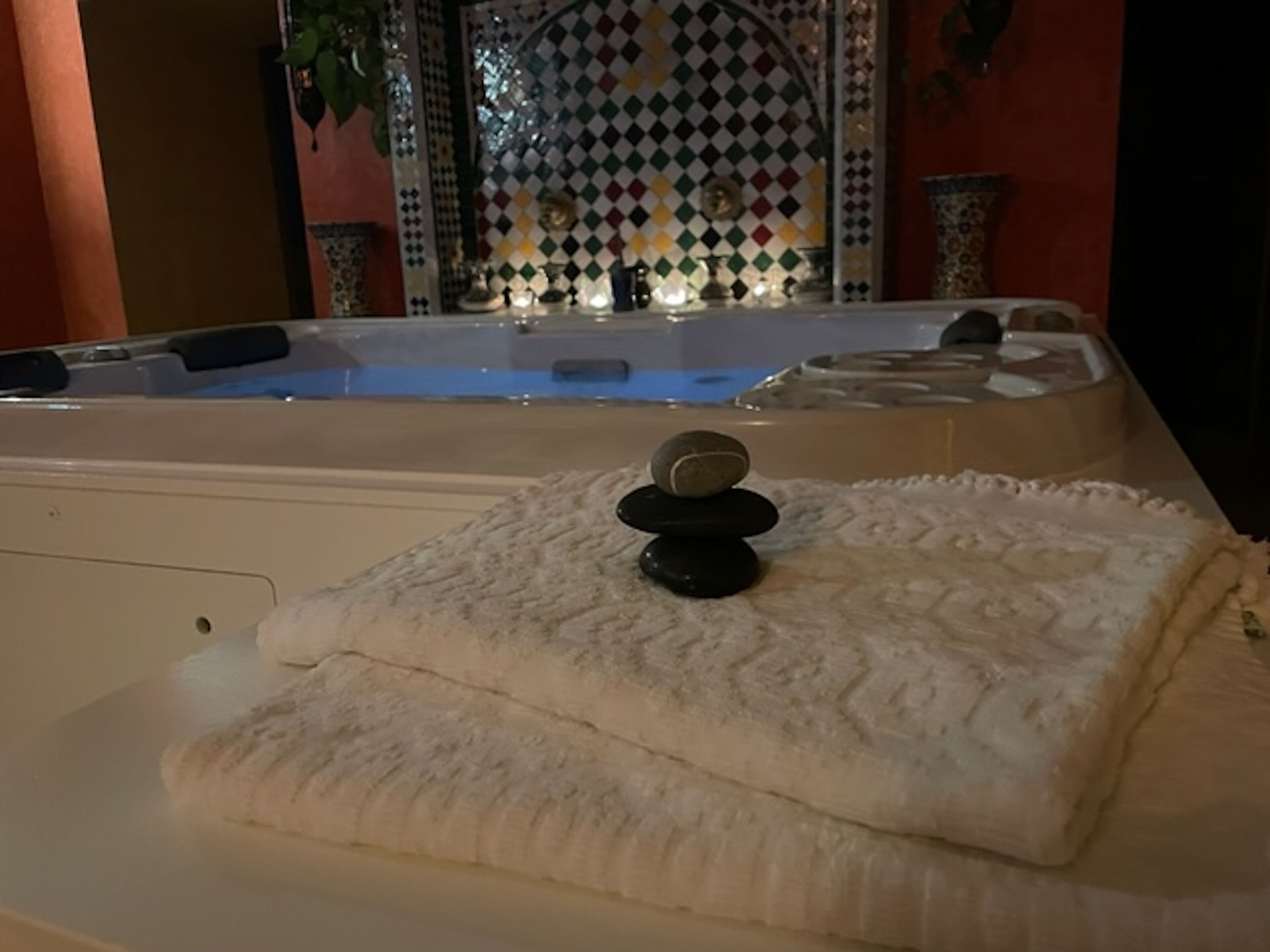 Een wellnessruimte met een jacuzzi, een handdoek en een decoratieve steencompositie.