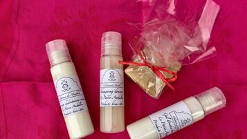 Vier flesjes lotion en een klein cadeautje op een roze doek.