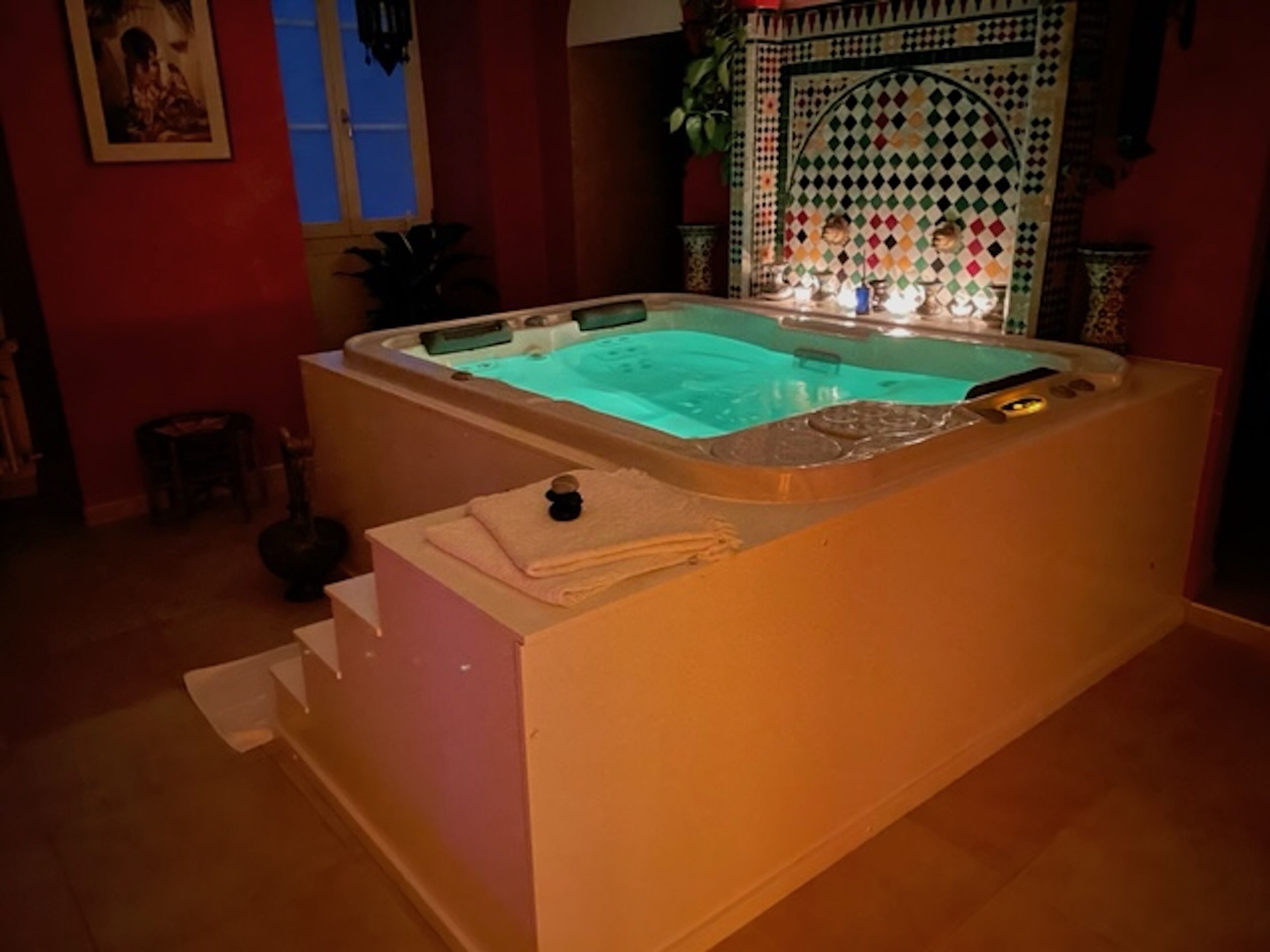 A hot tub in a room with a tiled wall and a window.