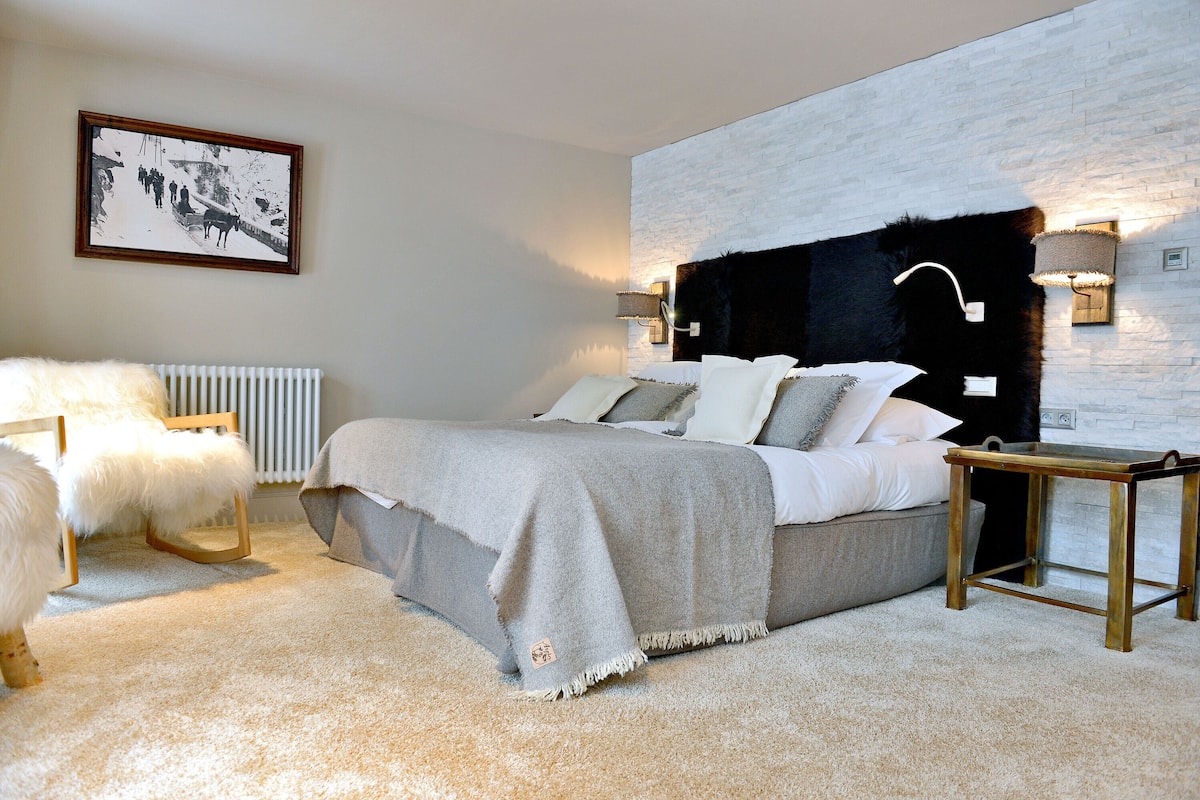 Une chambre à coucher comprenant un lit, une chaise, une table de chevet et une lampe fixée au mur.
