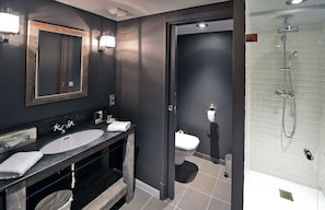 Een moderne badkamer met twee wasbakken, een spiegel en een douche.