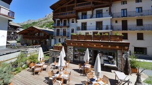 Una terraza de madera con mobiliario exterior y un muro de piedra.