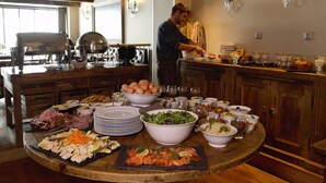 Una gran mesa de madera con diversos alimentos y una persona sirviendo.