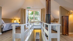 Une pièce avec un plafond haut, une cheminée, un escalier et une vue sur l’extérieur.