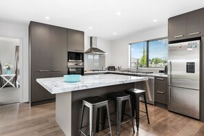 A modern kitchen with a large island, stainless steel appliances, and a view of the outdoors.