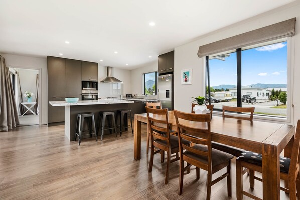 A modern kitchen with a central island, wooden dining table, and chairs.