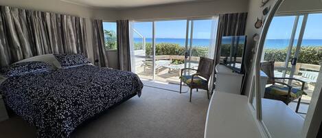 Une chambre dotée d’un grand lit, d’une télévision et d’un balcon offrant une vue sur la mer.