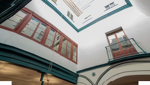 A multi-level interior with a white and teal color scheme, featuring a balcony with a red door and a window with a white frame. - Vivian's Guest House Auto Check-in (Jerez de la Frontera)