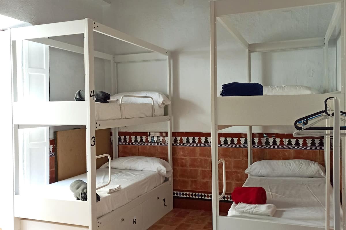 Un dormitorio con literas, suelo de baldosas y techo decorado.