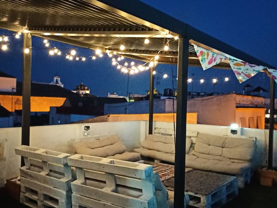 An outdoor seating area with string lights, a covered section, and outdoor furniture.