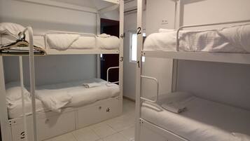 A bunk room with two bunk beds, a white metal ladder, and a tiled floor.
