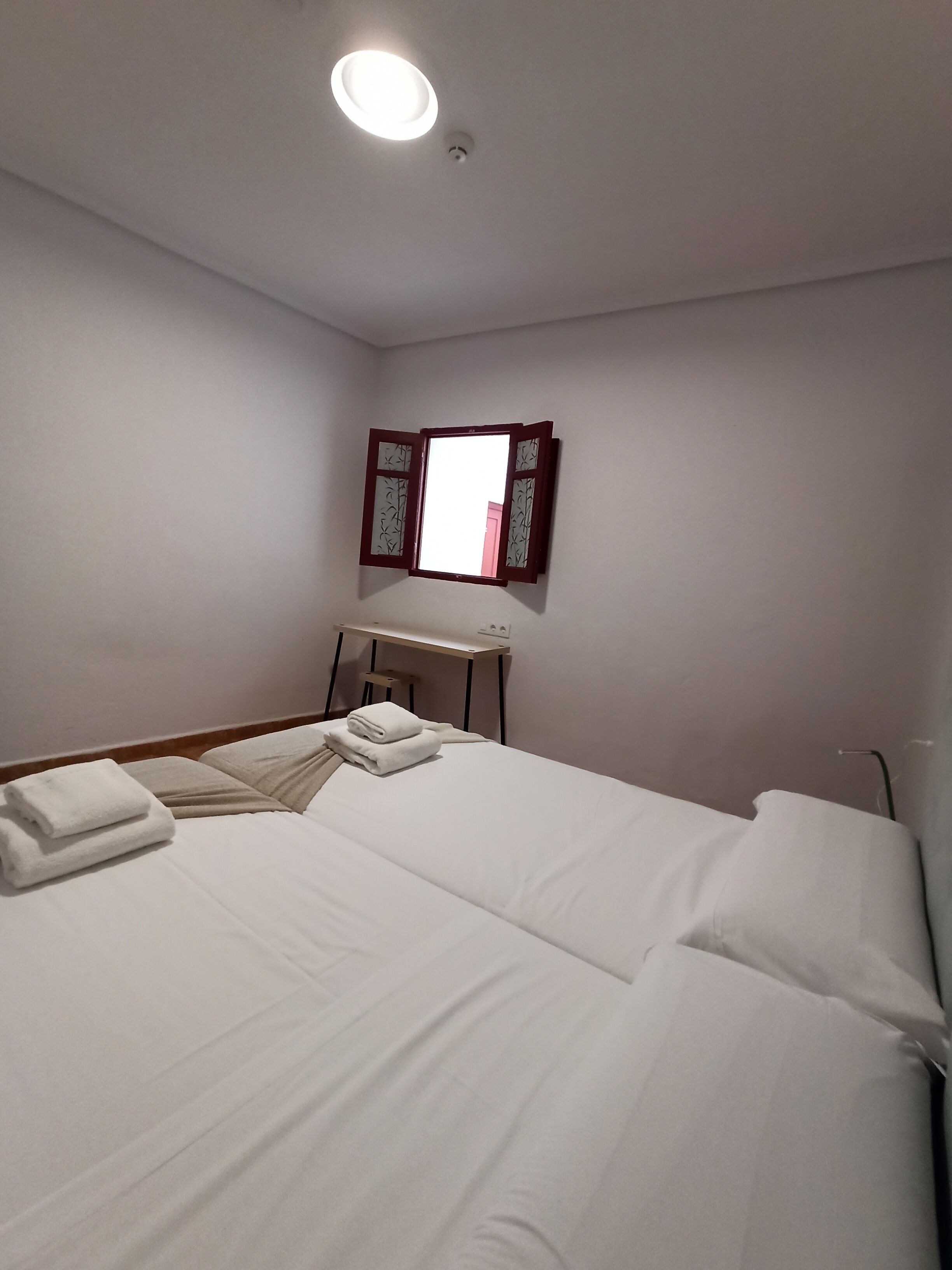 Een hotelkamer met een bed, een bureau en een spiegel aan de muur.