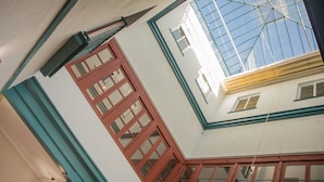 A corner of a building with a red-framed window, a blue-framed window, and a skylight. - Vivian's Guest House Auto Check-in (Jerez de la Frontera)