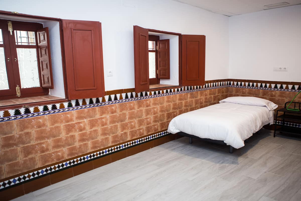 Un dormitorio con cama, ventana con vistas y puerta.