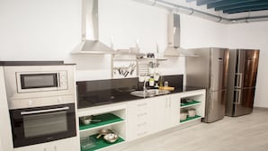 A modern kitchen with stainless steel appliances, white cabinets, and green shelves. - Vivian's Guest House Auto Check-in (Jerez de la Frontera)