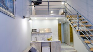 Um espaço compacto com cozinha compacta, sofá e escada.