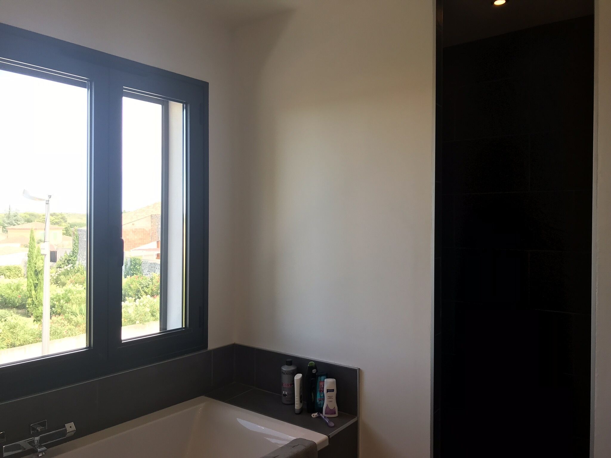 A modern bathroom with a bathtub, a window, and a shower area.