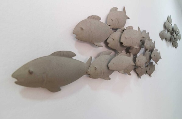 Une collection de sculptures de poissons en céramique, disposées sur une surface unie.
