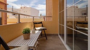 Ein Balkon mit Tisch, Stühlen, einem Blumentopf und Blick auf die Nachbargebäude.