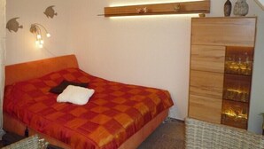A bedroom with a bed, a wooden dresser, wall-mounted sconces, and decorative fish silhouettes. - Wohnung Segelhafenidyll (Karlshagen)