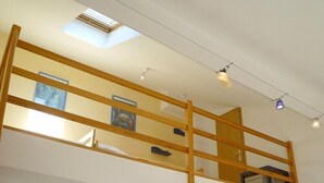A room with a loft bed, skylight, and a small kitchenette. - Wohnung Ostseeblick (Karlshagen)