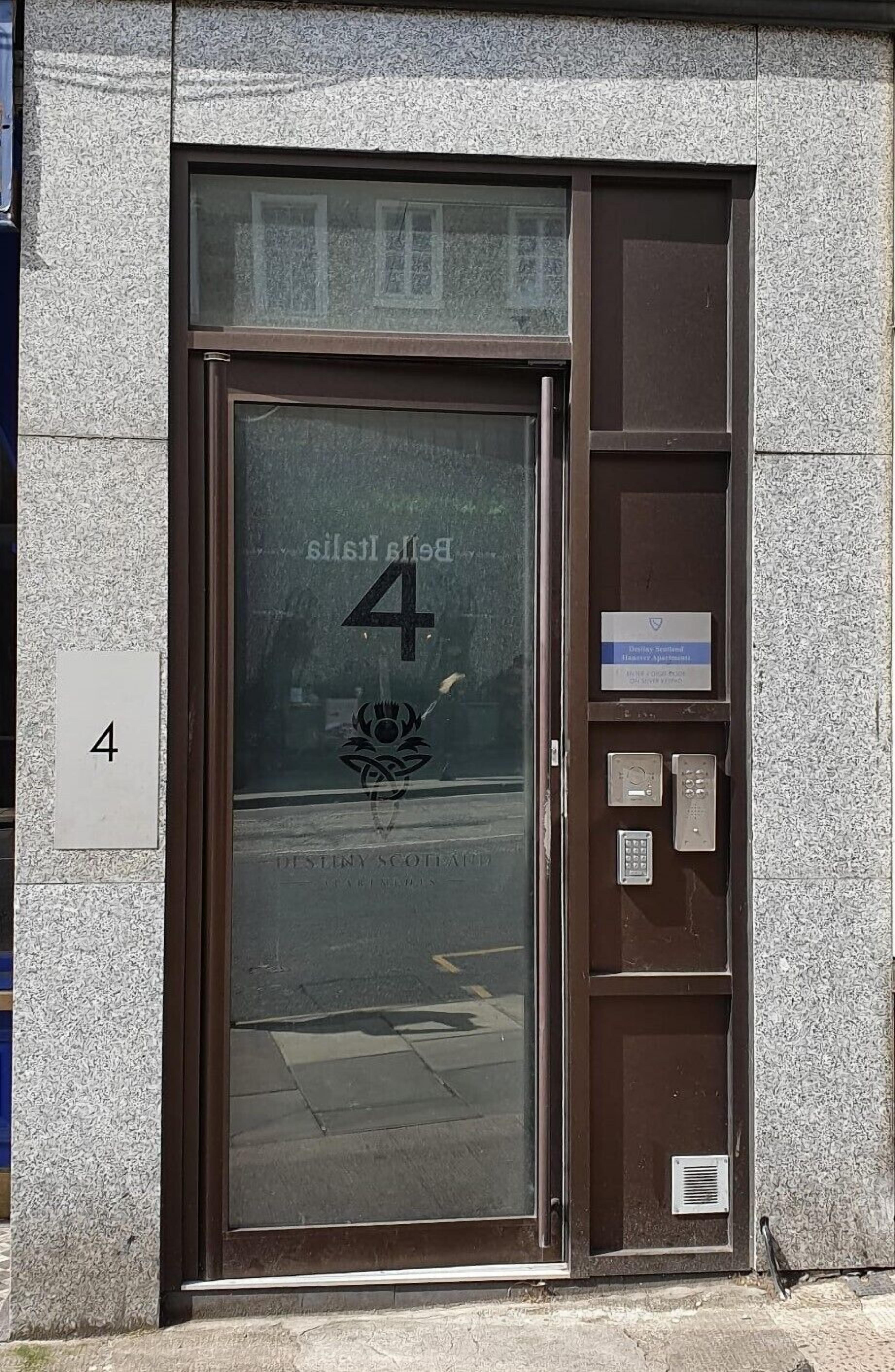 A building entrance with a glass door, a number '4' sign, and a keypad for access.